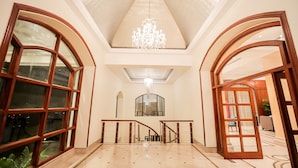 A spacious lobby with a high ceiling, a chandelier, and a staircase leading to another level. - Regenta Central Lucknow by Royal Orchid Hotels Limited (Lucknow)