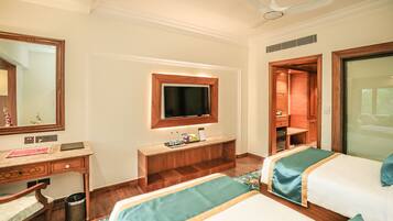 A hotel room with two beds, a desk, a mirror, a television, and a wardrobe.
