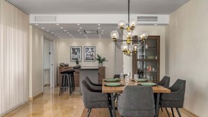 Un comedor con una mesa de madera, sillas tapizadas en gris y una araña.