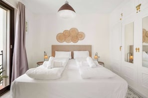A hotel room with a large bed, two bedside tables, a wall-mounted light fixture, and a mirror.