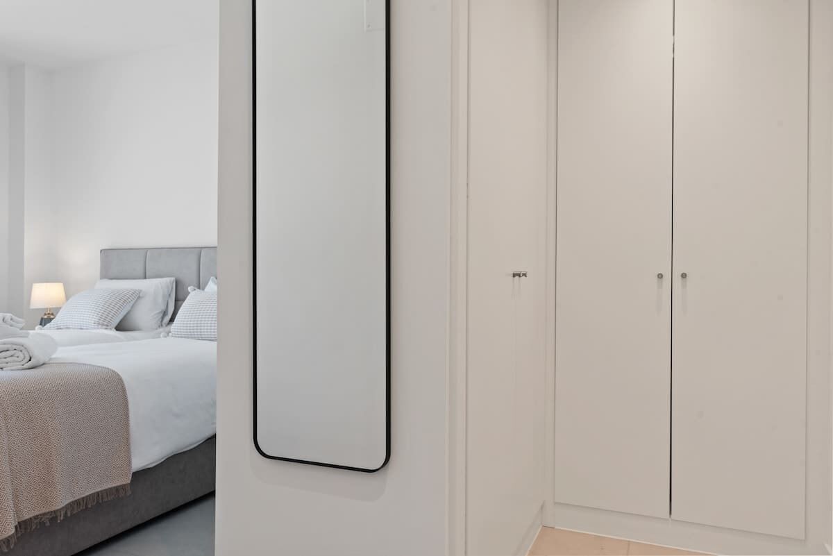 Une chambre moderne avec un grand lit, une table de chevet avec une lampe et une armoire.
