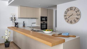 A modern kitchen with a wooden island, a built-in oven, and a wall clock. - Exclusive Seaview Apt by Costarentals - Ref 02 (Fuengirola)