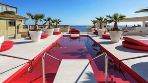 A rooftop pool area with red seating, palm trees, and a clear view of the sea. - Exclusive Seaview Apt by Costarentals - Ref 02 (Fuengirola)