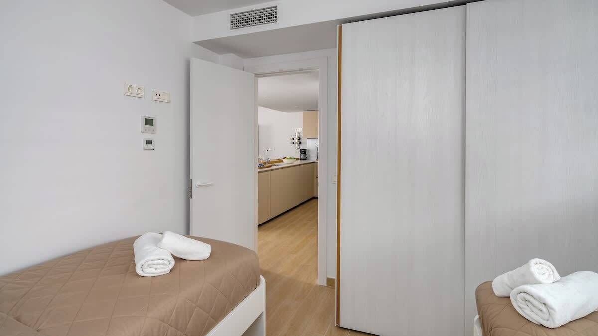 Habitació d'hotel amb dos llits, petita cuina i bany.