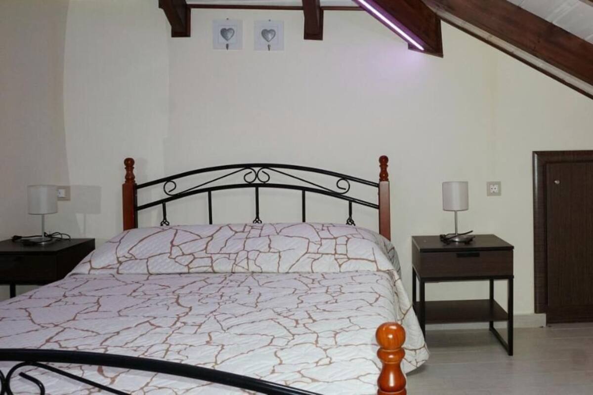 Une chambre à coucher avec un lit, des tables de chevet, une porte et un plafond avec des poutres apparentes.