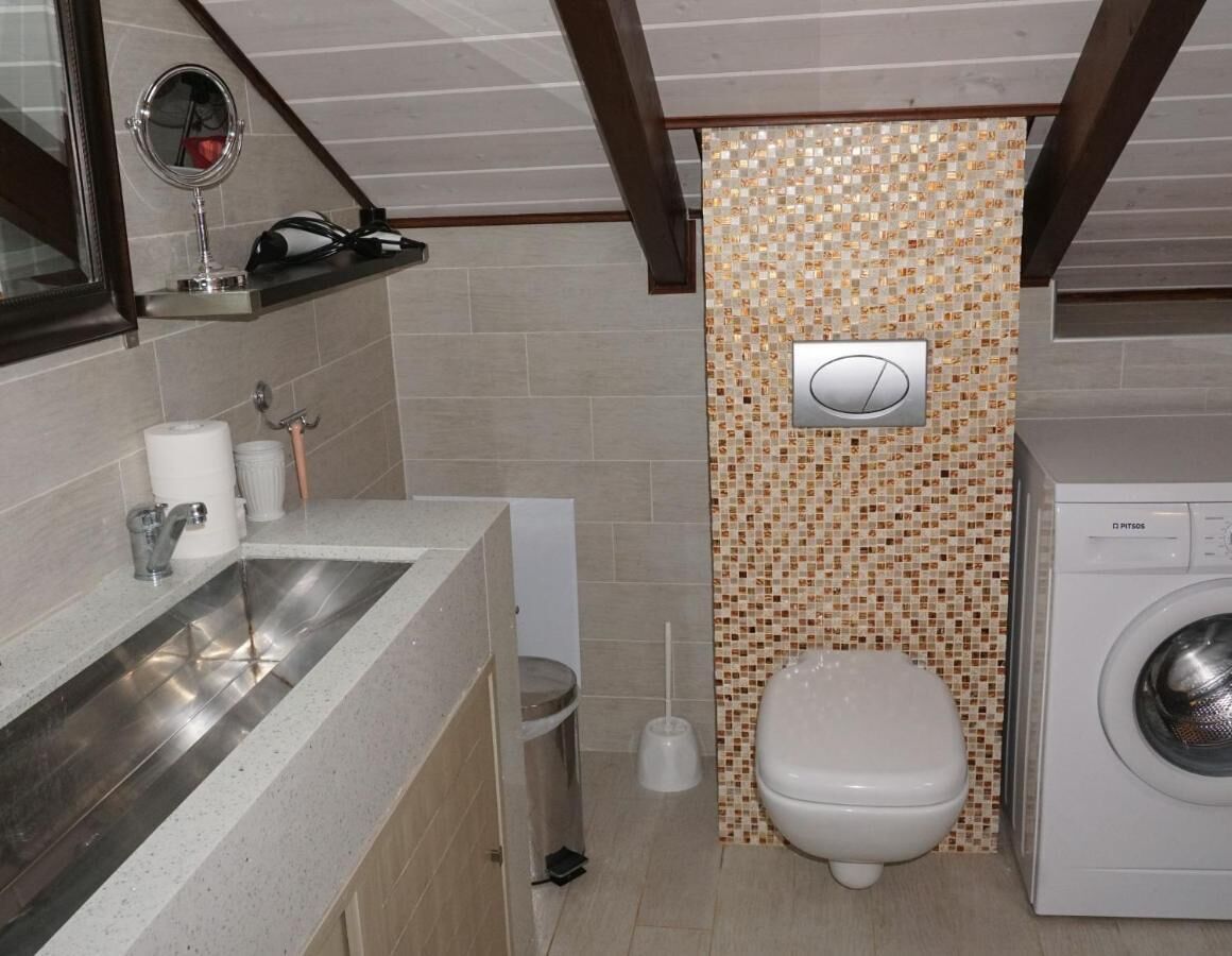 A compact bathroom with a sink, toilet, and washing machine.
