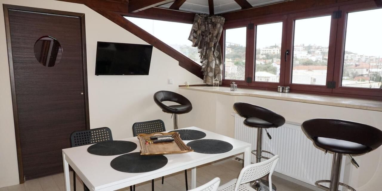 A dining area with a white table, black circular mats, and two black bar stools.