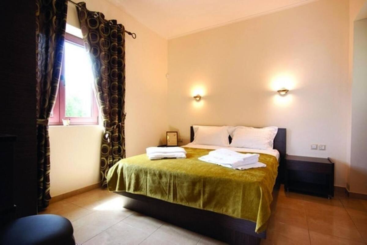 Une chambre à coucher avec un lit, deux lampes de chevet, une fenêtre avec des rideaux et une table de chevet.