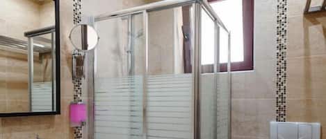 A modern bathroom with a glass shower enclosure, a sink with a mirror, and a toilet.
