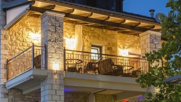 A stone building with a balcony and outdoor seating area. - Fegaropetra studios (Igoumenitsa)