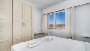 A hotel room with a bed, a window with a city view, a wardrobe, and a small table with a lamp. - Relaxing Getaway by Costarentals - Ref 169 (Fuengirola)