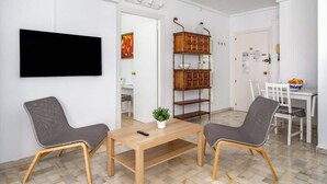 A modern living room with a TV, two chairs, a wooden table, and a decorative shelf. - Relaxing Getaway by Costarentals - Ref 169 (Fuengirola)