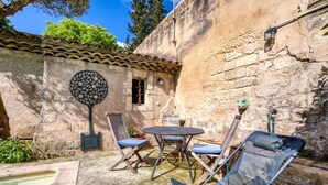 A stone building with a tiled roof, a small window, and a decorative wall piece. - Oasis Centre Charme House with Shared Pool, Wi-Fi, and Air Conditioning (Montpellier)