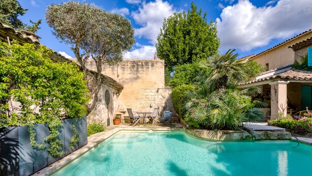 A swimming pool with lounge chairs and a stone wall. - Oasis Centre Charme House with Shared Pool, Wi-Fi, and Air Conditioning (Montpellier)