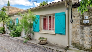 A building with a stone wall, a window with red shutters, and a number plaque. - Oasis Centre Charme House with Shared Pool, Wi-Fi, and Air Conditioning (Montpellier)