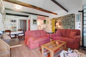 Un salon chaleureux avec un canapé rose, une table basse en bois et un mur en pierre.