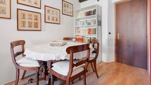 Un coin repas comprenant une table, des chaises, des tableaux encadrés et une bibliothèque.