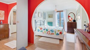 Une chambre à coucher avec un lit, une commode, un miroir et une vue sur l’extérieur.