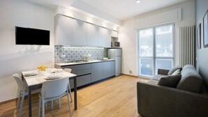 A modern kitchen with a dining area, a flat-screen TV, and a sofa. - ‘Victoria Family’ Apartment with Balcony, Wi-Fi & Air Conditioning (Diano Marina)