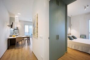 Une chambre d’hôtel moderne comprenant un lit, un bureau avec une chaise, une table à manger et une grande armoire.