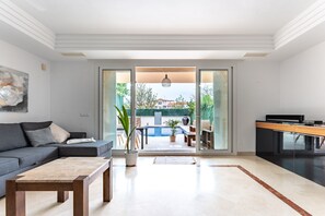 A modern living room with a sofa, coffee table, and a view of an outdoor pool area.