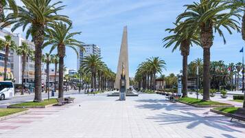 A public square with a tall obelisk, palm trees, benches, and a McDonald's restaurant.