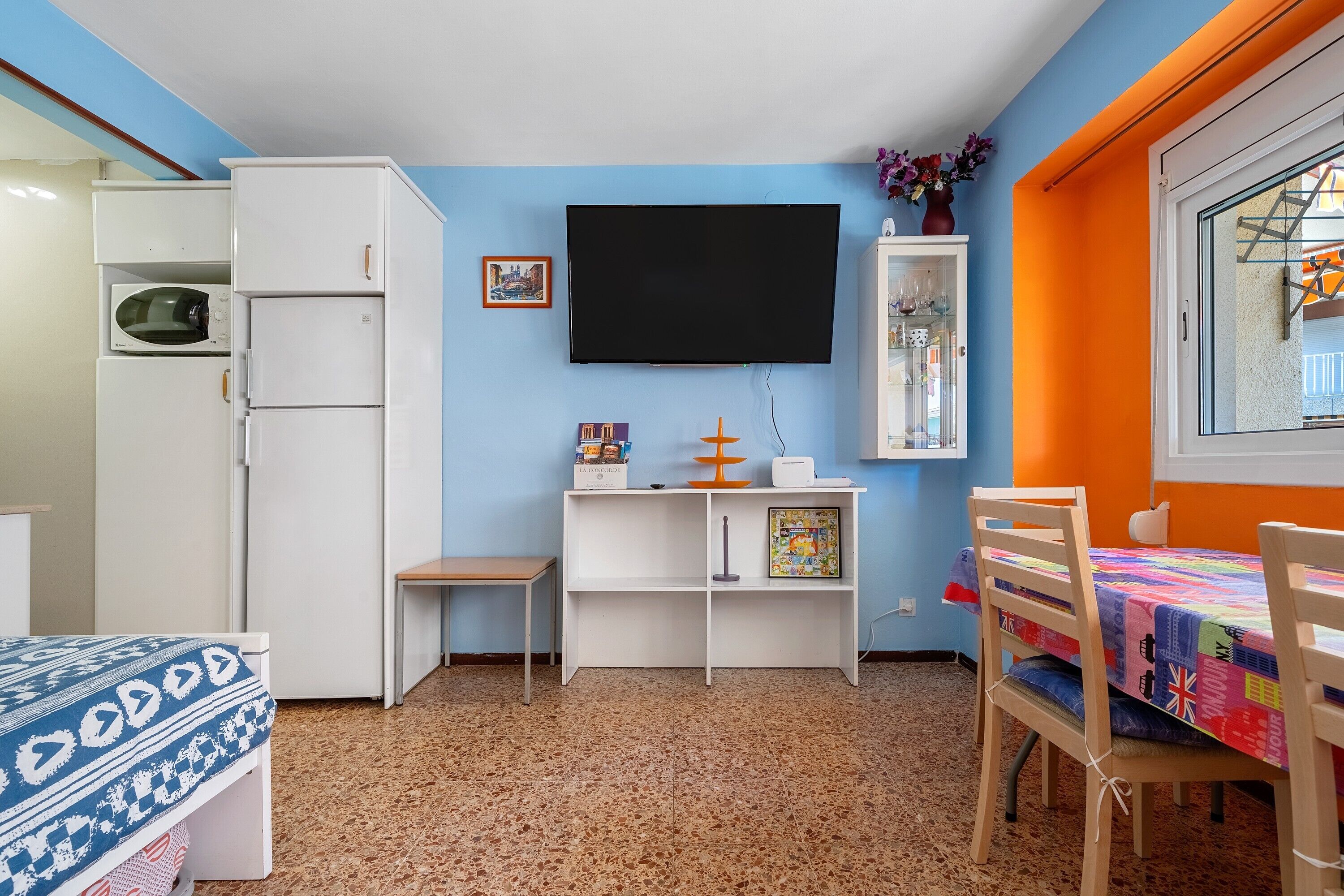 A compact room with a bed, a desk, a TV, and a small cabinet.