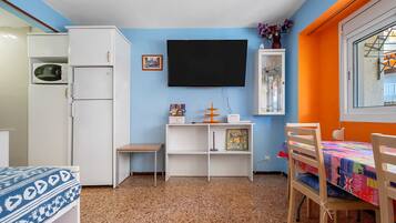A compact room with a bed, a desk, a TV, and a small cabinet.