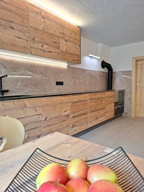 Una cocina moderna con armarios de madera, salpicadero de mármol y un lavamanos negro.
