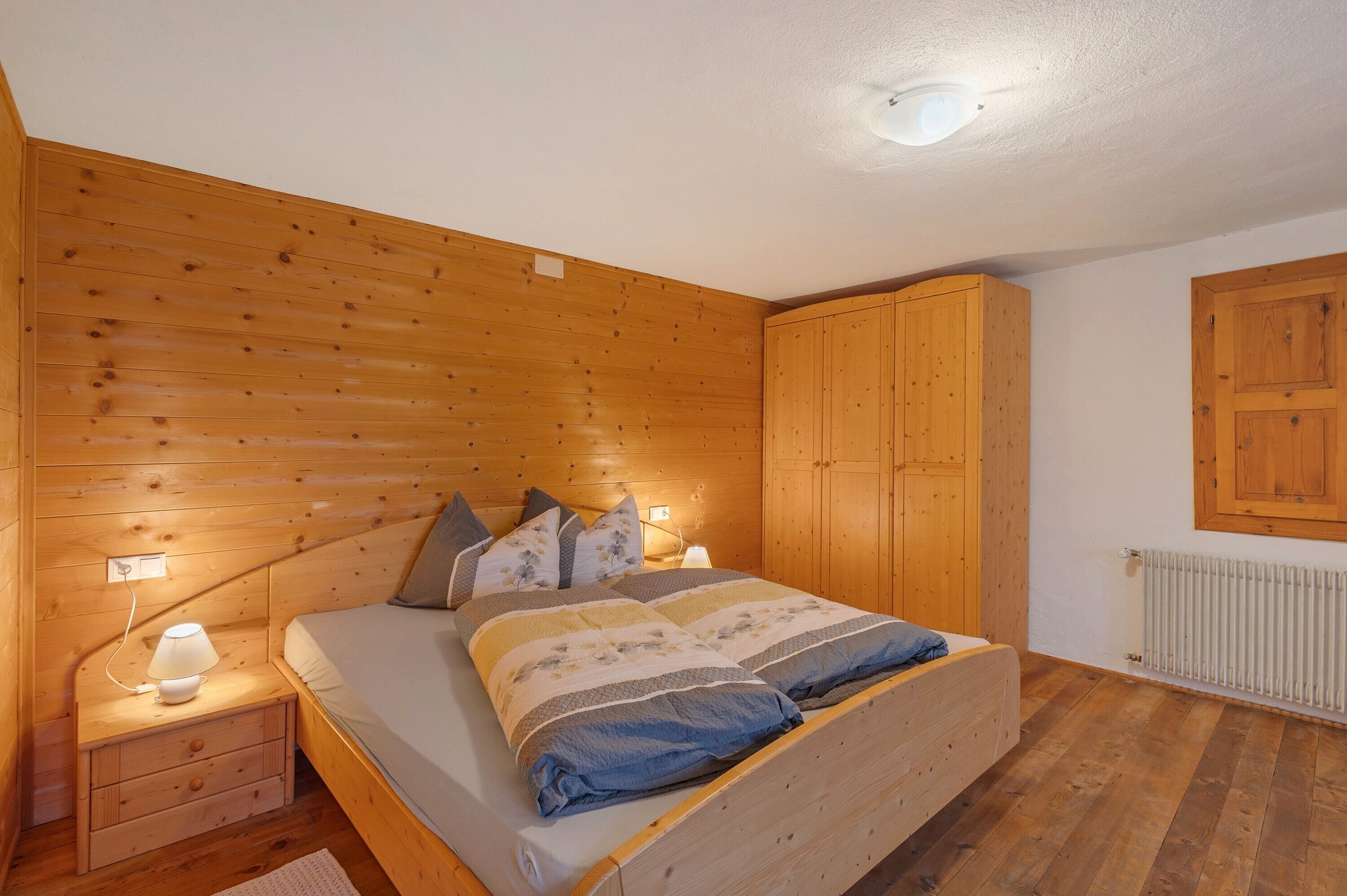 A wooden-paneled bedroom with a bed, nightstands, and a wardrobe.