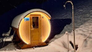 Une cabane en bois avec une entrée circulaire, une porte et une petite enseigne au-dessus de la porte.