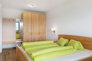 A bedroom with a bed, wooden wardrobe, and a nightstand.