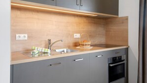 Een moderne keuken met een inbouwoven, een spoelbak en een houten aanrecht.