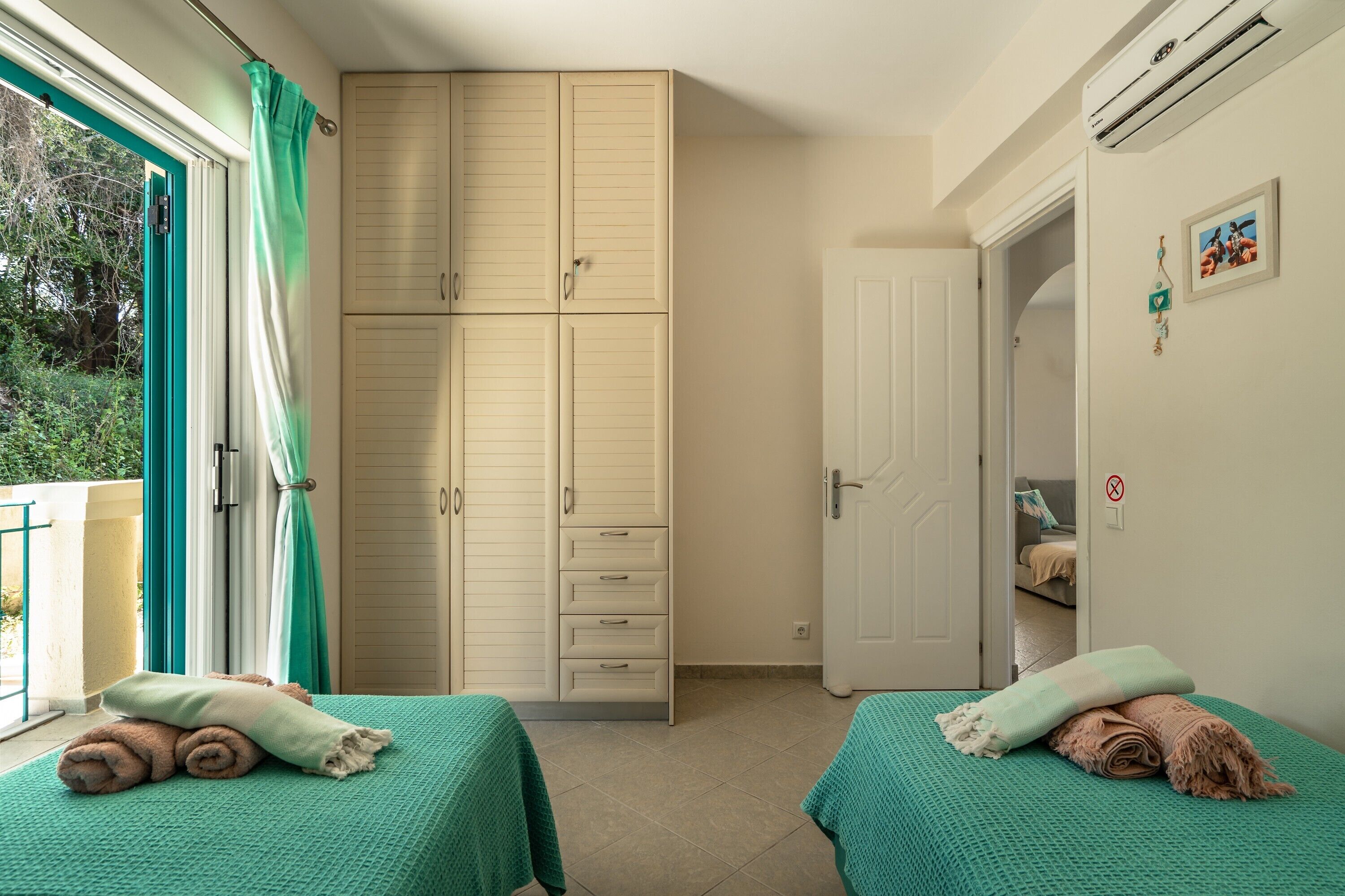 Un dormitorio con dos camas, un armario y la puerta de un baño.