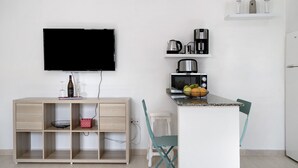 A modern kitchen with a flat-screen TV, a coffee maker, a microwave, and a fruit bowl.