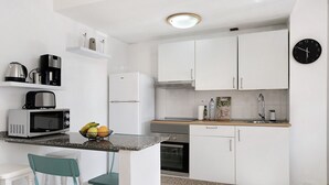 A modern kitchen with white cabinets, a microwave, a toaster, and a sink.
