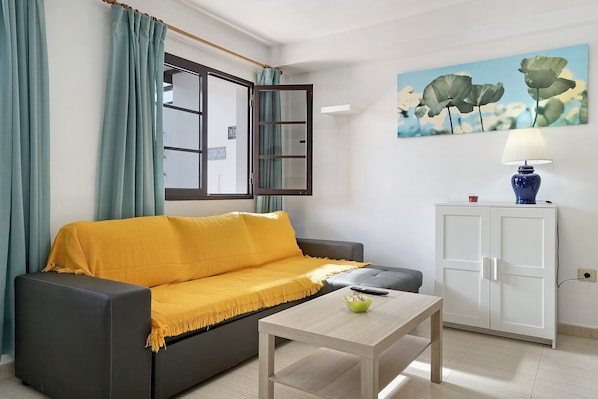 Un salon avec un canapé, une table, un meuble et un tableau accroché au mur.