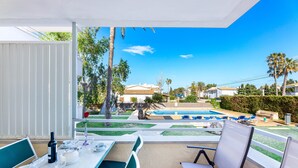 Un balcon avec une table dressée pour le dîner, une piscine et une vue sur les environs.