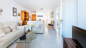 Un salon moderne comprenant un canapé, une table basse, un téléviseur et un coin repas avec des chaises et une table.