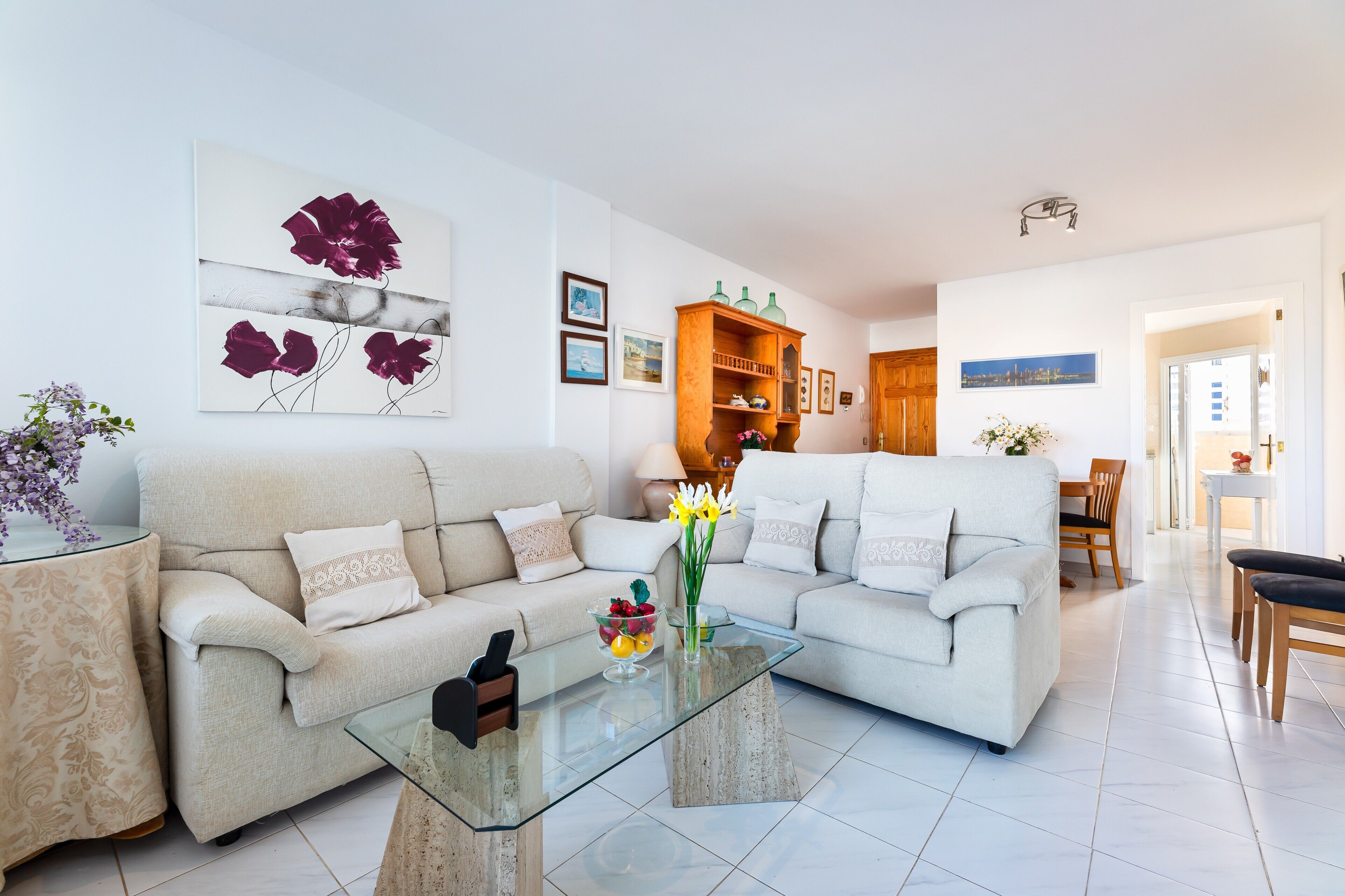 Een moderne woonkamer met twee banken, een glazen salontafel en een houten kast.
