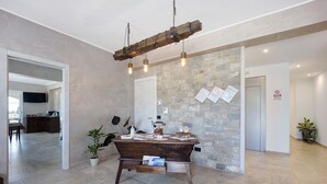 Une pièce spacieuse avec une table en bois rustique, un mur en pierre et, au fond, une cuisine moderne.