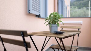 A small wooden table with a potted plant and a smartphone on it, a wooden chair, and a window with shutters. - Holiday Apartment "Antichi Ricordi - Da Angela" with Balcony, Shared Pool & Wi-Fi (Andora)