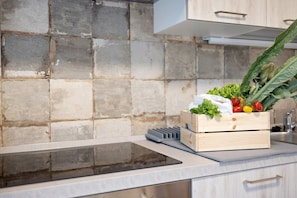 A kitchen with a stone backsplash, a wooden crate with vegetables, a digital scale, and a modern stove. - Holiday Apartment "Antichi Ricordi - Da Angela" with Balcony, Shared Pool & Wi-Fi (Andora)