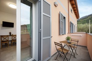 A balcony with a table and chairs, a potted plant, and a sliding glass door.