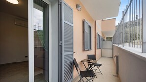 A balcony with a table and chairs, a sliding glass door, and a metal railing. - Holiday Apartment "Antichi Ricordi - La Stalla" with Terrace, Shared Pool & Wi-Fi (Andora)