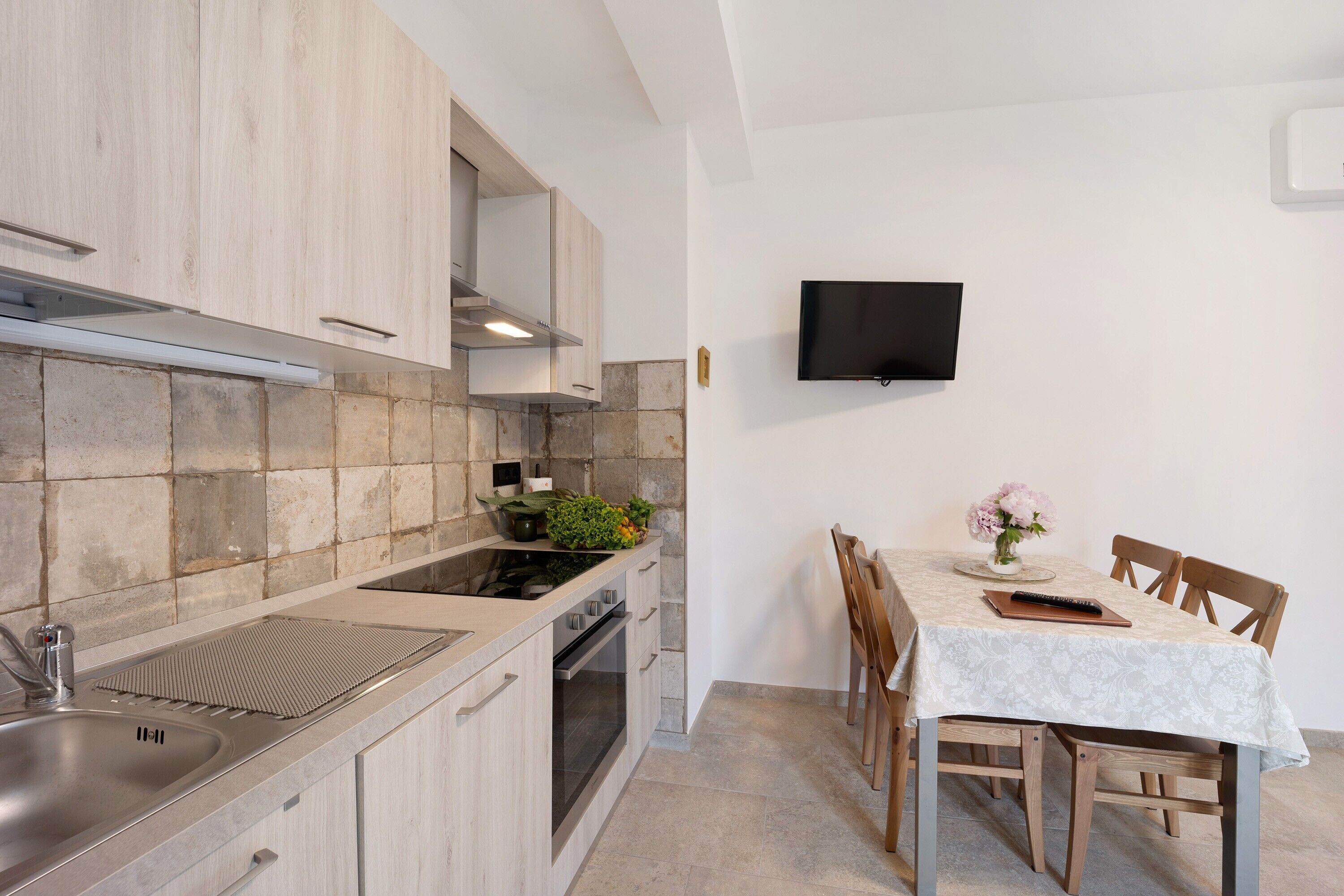 A modern kitchen with a built-in stove, a sink, and a dining area with a table and chairs.