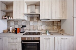 A modern kitchen with a built-in oven, a stovetop, a sink, and wooden cabinets.