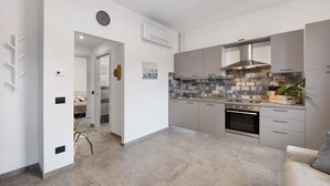 Una cocina moderna con armarios grises, salpicadero de azulejos y horno empotrado.