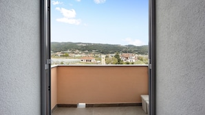 Un balcón con vista a una zona residencial y colinas.