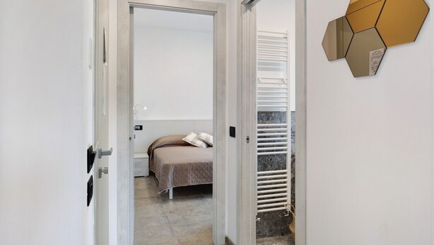 Un dormitorio con cama, una puerta y un adorno geométrico en la pared.